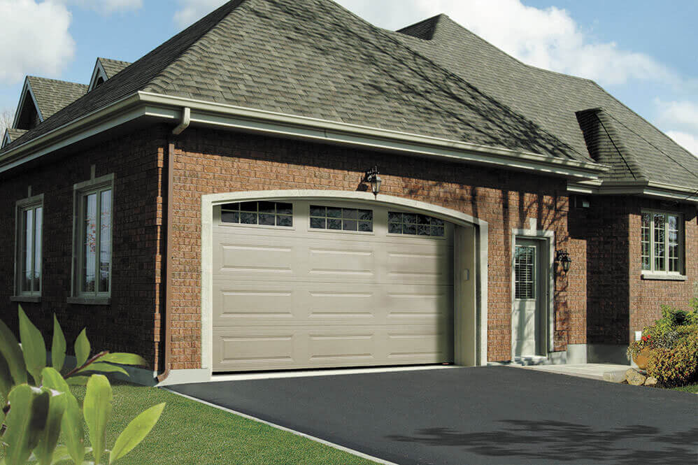 classic claystone 8 lite fiberglass garage door in tan with three windows at the top on a brick house